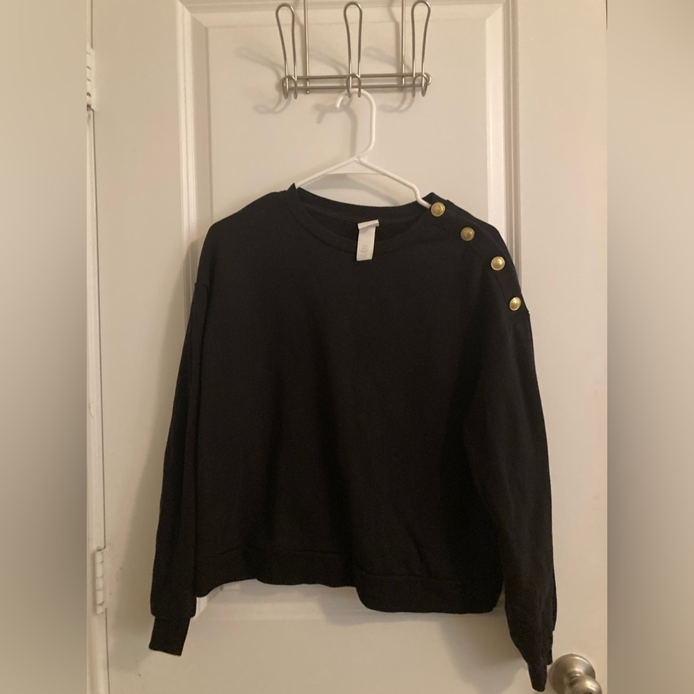 Women’s size medium H&M black sweater with gold button shoulder trim.